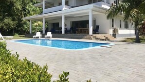 A two-story house with a swimming pool, white exterior, and a covered patio area.
