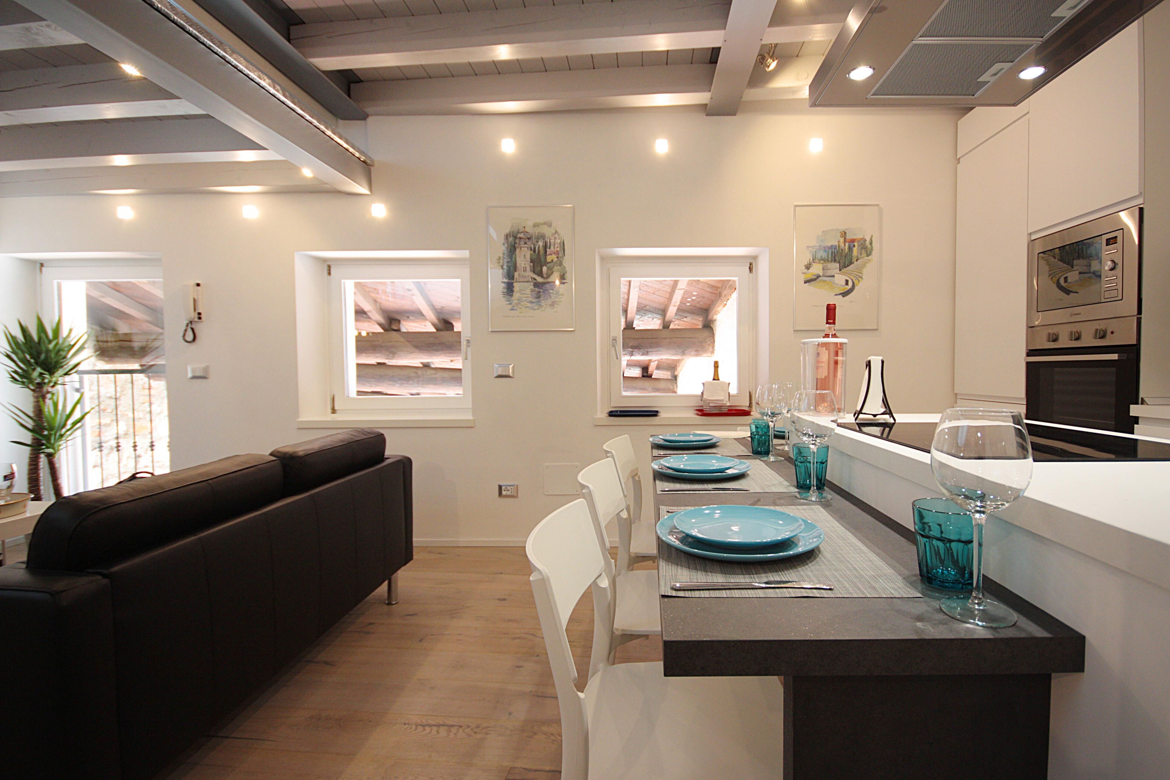 A modern kitchen with white cabinetry, a built-in oven, and a dining area with a long table and blue plates.
