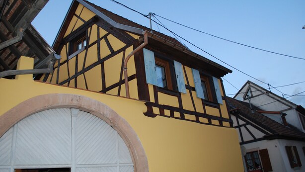 Un bâtiment traditionnel à colombages, doté d’une grande entrée en arc de cercle et de nombreuses fenêtres.