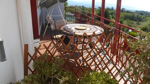 Ein Balkon mit rundem Tisch, Stühlen und einem überdachten Bereich.