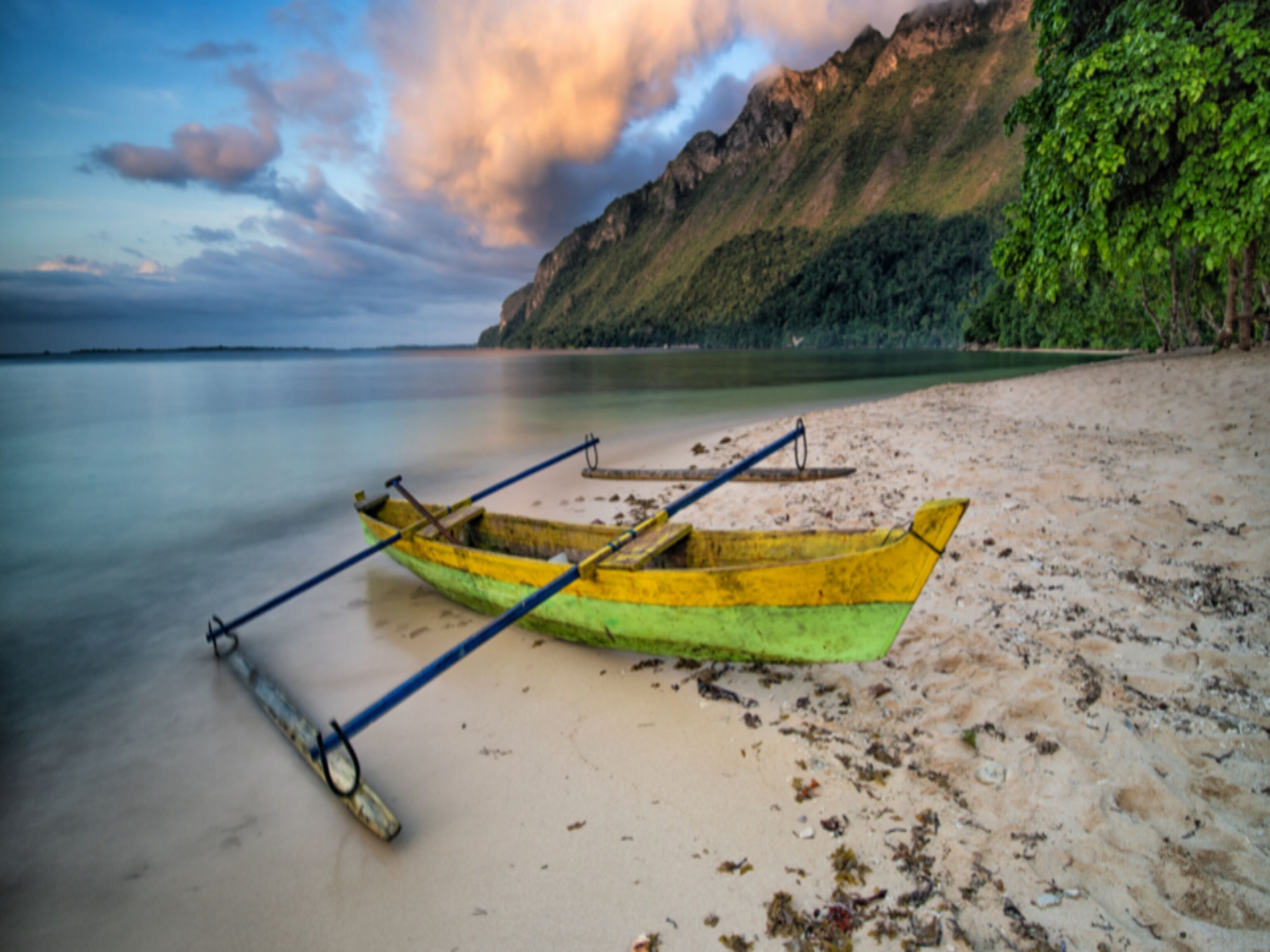 A beach with a yellow boat on the sand.