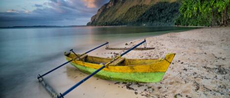 A beach with a yellow boat on the sand.