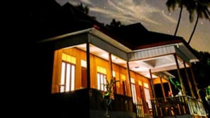 Ett hus med en inglasad veranda, en träfasad och utsikt över natthimlen med stjärnor.