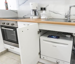 A kitchen with a built-in oven, a coffee maker, and a mini fridge.