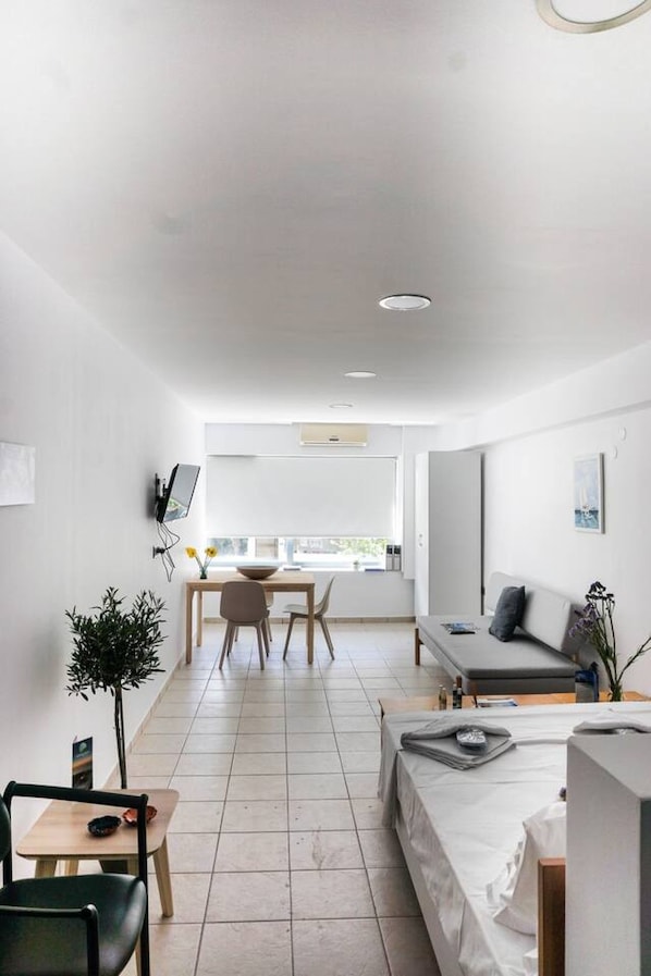 A modern, well-lit living area with a dining table, sofa, and a view of the outdoors.