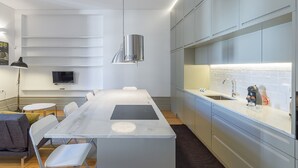 Eine moderne Küche mit Marmorarbeitsplatte, eingebauten Geräten und einer großen Kochinsel mit Sitzgelegenheiten.