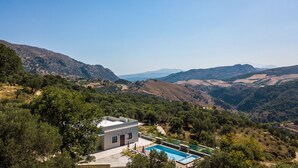 Une villa moderne dotée d’une piscine, entourée d’une végétation luxuriante et de montagnes.