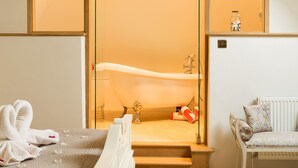 Camera da letto con una grande finestra, un lampadario, una vasca da bagno e una panca.