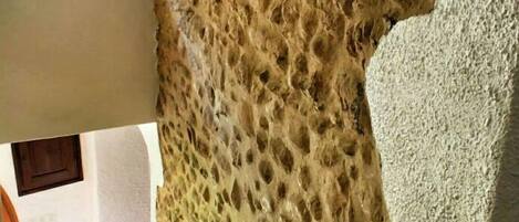 Una stanza con un muro strutturato, un divano bianco e un pavimento in legno.