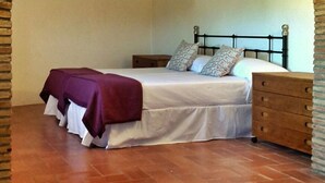 Een slaapkamer met een bed, een houten dressoir en een gewelfde boog van baksteen.