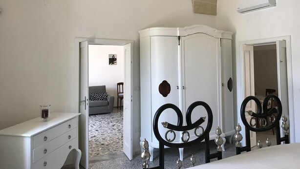 Een slaapkamer met een witte kledingkast, een dressoir en een bed met hoofdeinde.