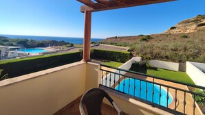 En balkon med udsigt over en swimmingpool og havet.