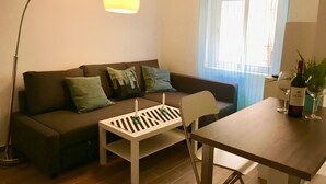 A modern living room with a sofa, a coffee table, a dining table, and a floor lamp.