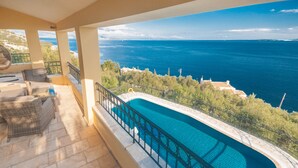 Uma varanda com piscina, móveis de exterior e vista para o mar.