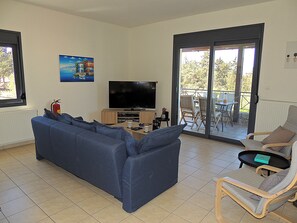 A living room with a sofa, a television, and a dining area with chairs and a table.