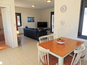 A living room with a sofa, TV, and a dining table with chairs. - A Recently Refurbed 3 Bedrm Villa, Large Pool, Great Privacy, Close to Amenities (Chania)