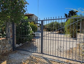 A gated entrance to a villa named 'Villa Pegasus' with a clear view of the surrounding greenery and a stone wall.