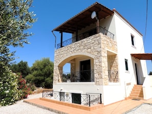 A two-story house with a stone facade, a balcony, and a satellite dish.