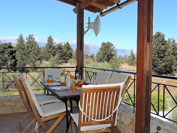 A wooden table with chairs, a satellite dish, and a mountain view.