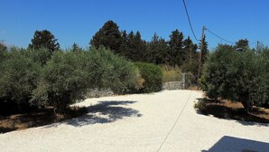A gravel driveway leading to a stone wall, surrounded by olive trees and a clear blue sky. - A Recently Refurbed 3 Bedrm Villa, Large Pool, Great Privacy, Close to Amenities (Chania)
