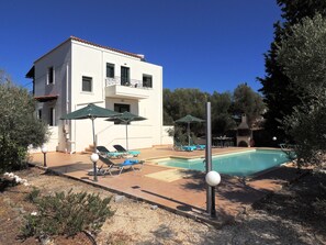A two-story building with a swimming pool, outdoor seating, and a garden area.