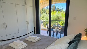 A bedroom with a bed, a balcony with a table and chairs, and a view of greenery. - A Recently Refurbed 3 Bedrm Villa, Large Pool, Great Privacy, Close to Amenities (Chania)