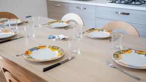 Une table à manger dressée avec des assiettes, des verres, des couverts et un porte-serviettes.
