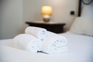 A neatly made bed with rolled white towels and a bedside lamp in the background. - Comfortable new villa, quiet and relaxing Tuscan countryside, nature, sun, sea (Camaiore)