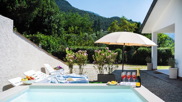 A pool area with lounge chairs, a table with fruit and drinks, and a view of greenery and hills. - Comfortable new villa, quiet and relaxing Tuscan countryside, nature, sun, sea (Camaiore)