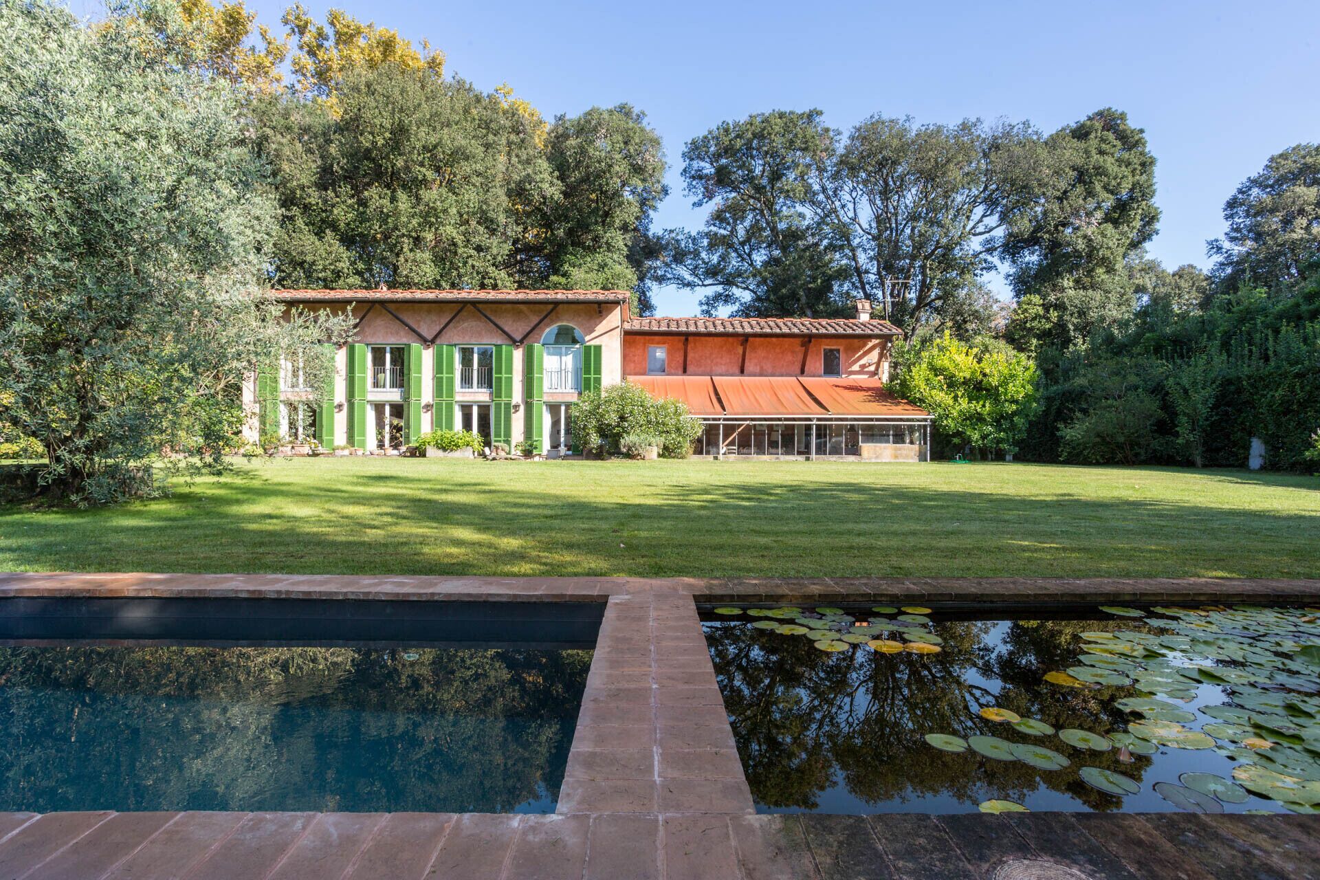 Una casa de dos pisos con una piscina al frente.