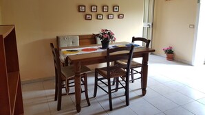 Un comedor con una mesa y sillas, una planta en maceta y un plato en la pared.