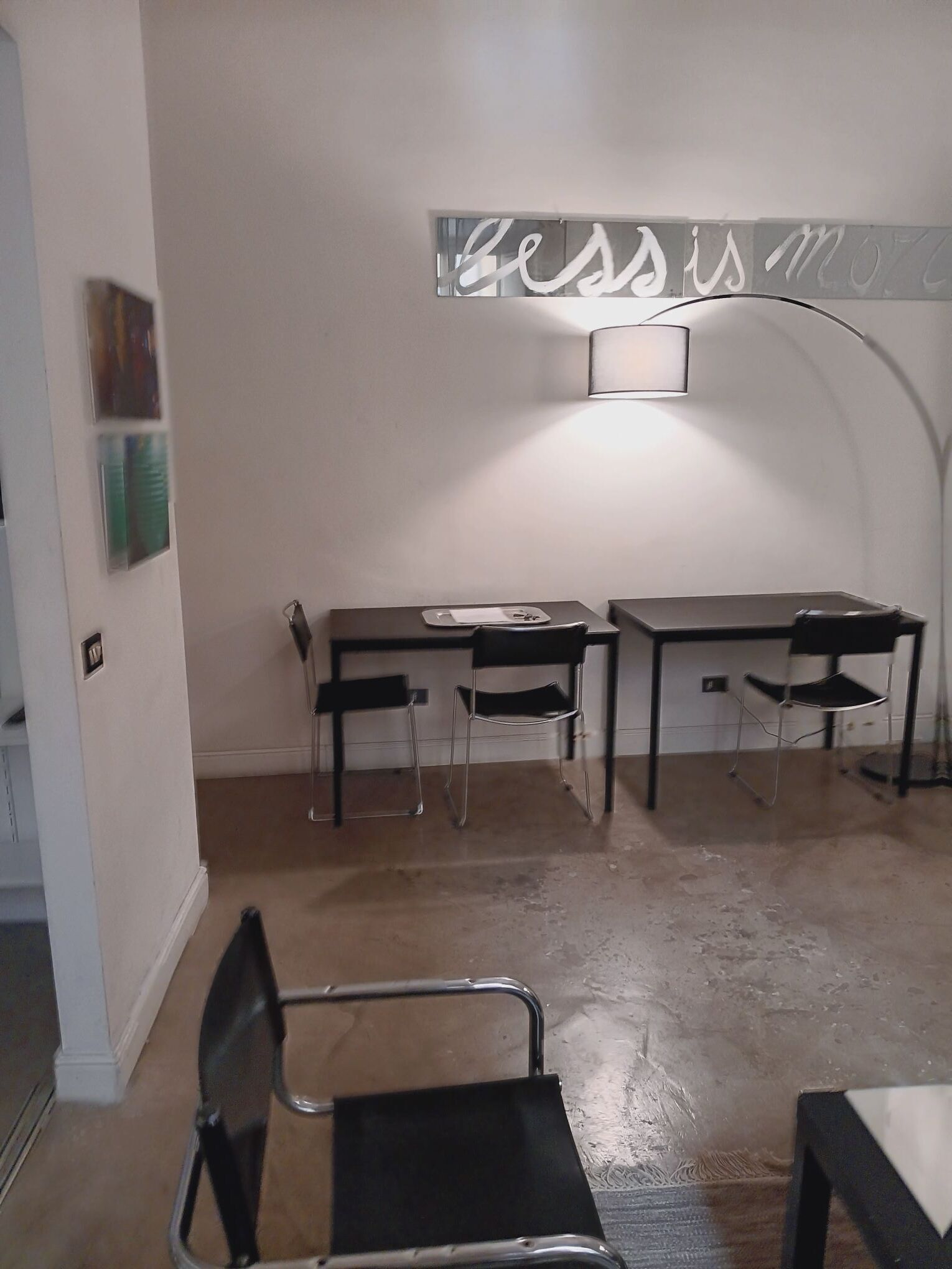 A room with two desks, two chairs, a lamp, and a wall-mounted sign.