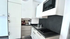 A modern kitchen with white cabinetry, a black countertop, and a built-in microwave.