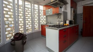 A modern kitchen with red cabinets, a gas stove, and a large window with a view of a building.