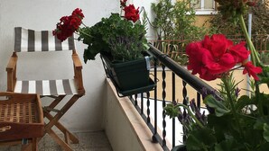 A balcony with a striped chair, a small table, and potted plants.