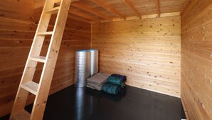 Un dormitorio abuhardillado de madera con una escalera, un calentador y una pila de mantas dobladas.