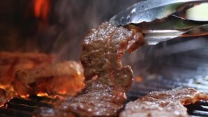 Una parrilla con carne asándose a fuego abierto.