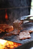 Una parrilla con carne asándose a fuego abierto.