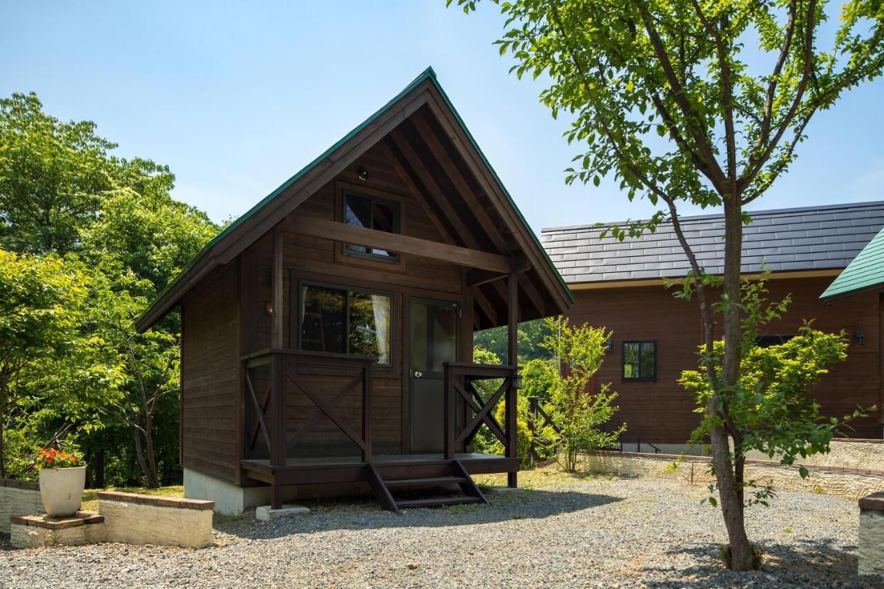 Une cabane en bois avec un toit en pente, une véranda et une allée gravillonnée.