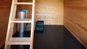Una cabaña de madera con un altillo, una escalera y un piso negro.