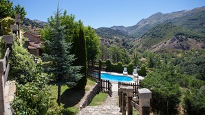 A pool surrounded by a wooden fence, set against a backdrop of mountains and greenery. - La Majada de Peñacorada I C.R Ideal with children in the foothills of Picos de Europa (Fuentes de Peñacorada)
