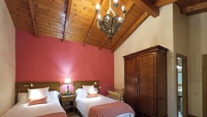 A bedroom with two beds, a wooden wardrobe, a chandelier, and a red wall. - La Majada de Peñacorada I C.R Ideal with children in the foothills of Picos de Europa (Fuentes de Peñacorada)