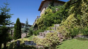A stone building with a sloped roof, surrounded by lush greenery and a small water feature. - La Majada de Peñacorada I C.R Ideal with children in the foothills of Picos de Europa (Fuentes de Peñacorada)