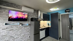 A modern kitchen with a built-in microwave, a stainless steel refrigerator, a sink, and a clock on the wall. - Studio Gruissan plage wifi piscine, clim, parking, équipée 4 pers, RDC, terrasse sud (Gruissan Plage)