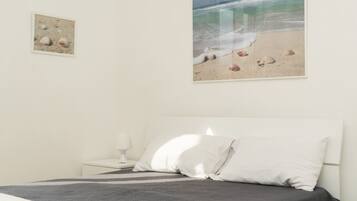 Een slaapkamer met een bed, een nachtkastje, een lamp en decoratie met een strandthema.
