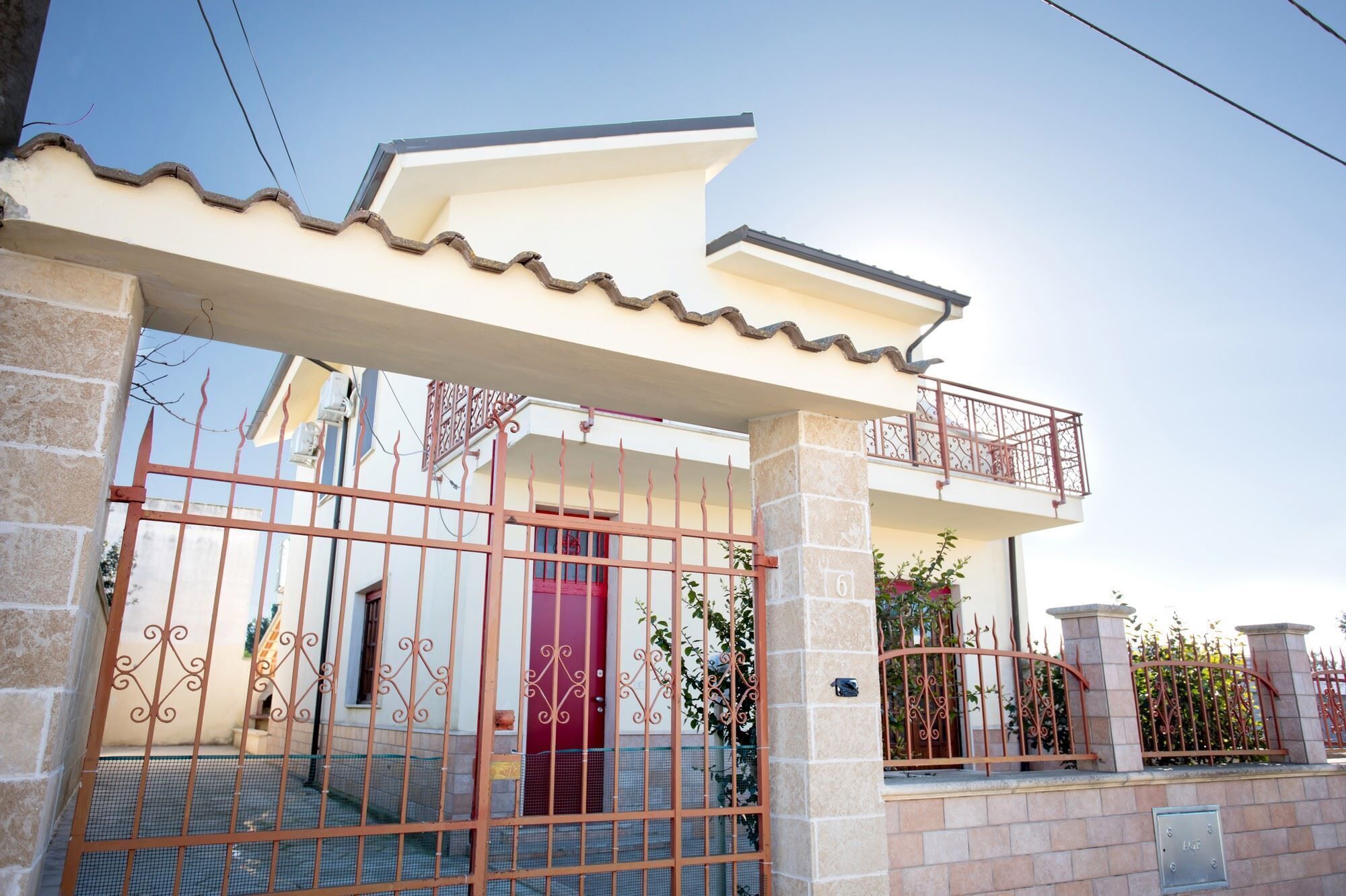 Un edificio residenziale con ingresso carrabile, un balcone e un pilastro in pietra con il numero 6.