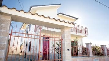 Un edificio residenziale con ingresso carrabile, un balcone e un pilastro in pietra con il numero 6.