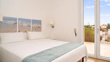 Ein Schlafzimmer mit Bett, Meerblick durch eine Glastür und einem Balkon mit Geländer.