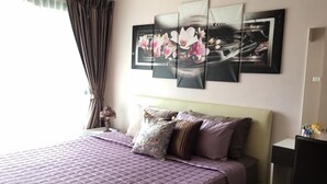 Une chambre à coucher comprenant un lit, une table de chevet, une lampe et un mur orné de trois œuvres d’art encadrées.
