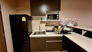 Une cuisine compacte comprenant un réfrigérateur noir, un four à micro-ondes, un évier et un petit plan de travail.